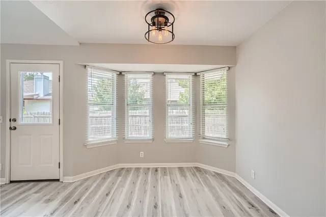 an empty room with wooden floor fireplace and windows