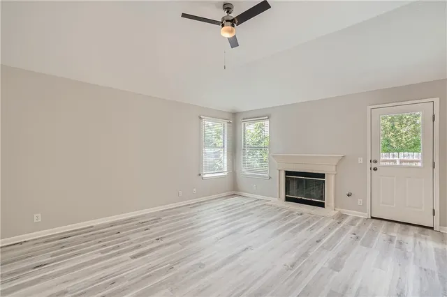 an empty room with windows fireplace and wooden floor
