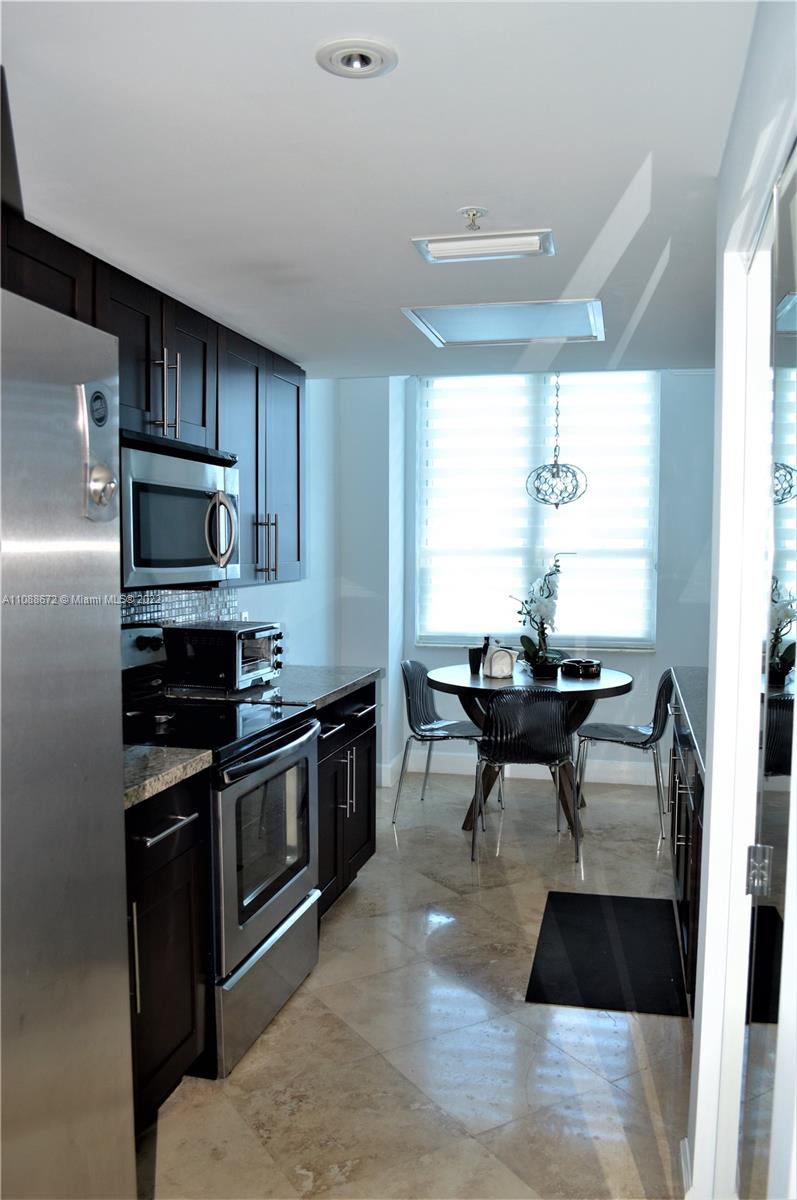701 Brickell Key Boulevard, Unit 1203 Miami, FL 33131 - Photo 19 of 34 a kitchen with granite countertop a stove and a refrigerator