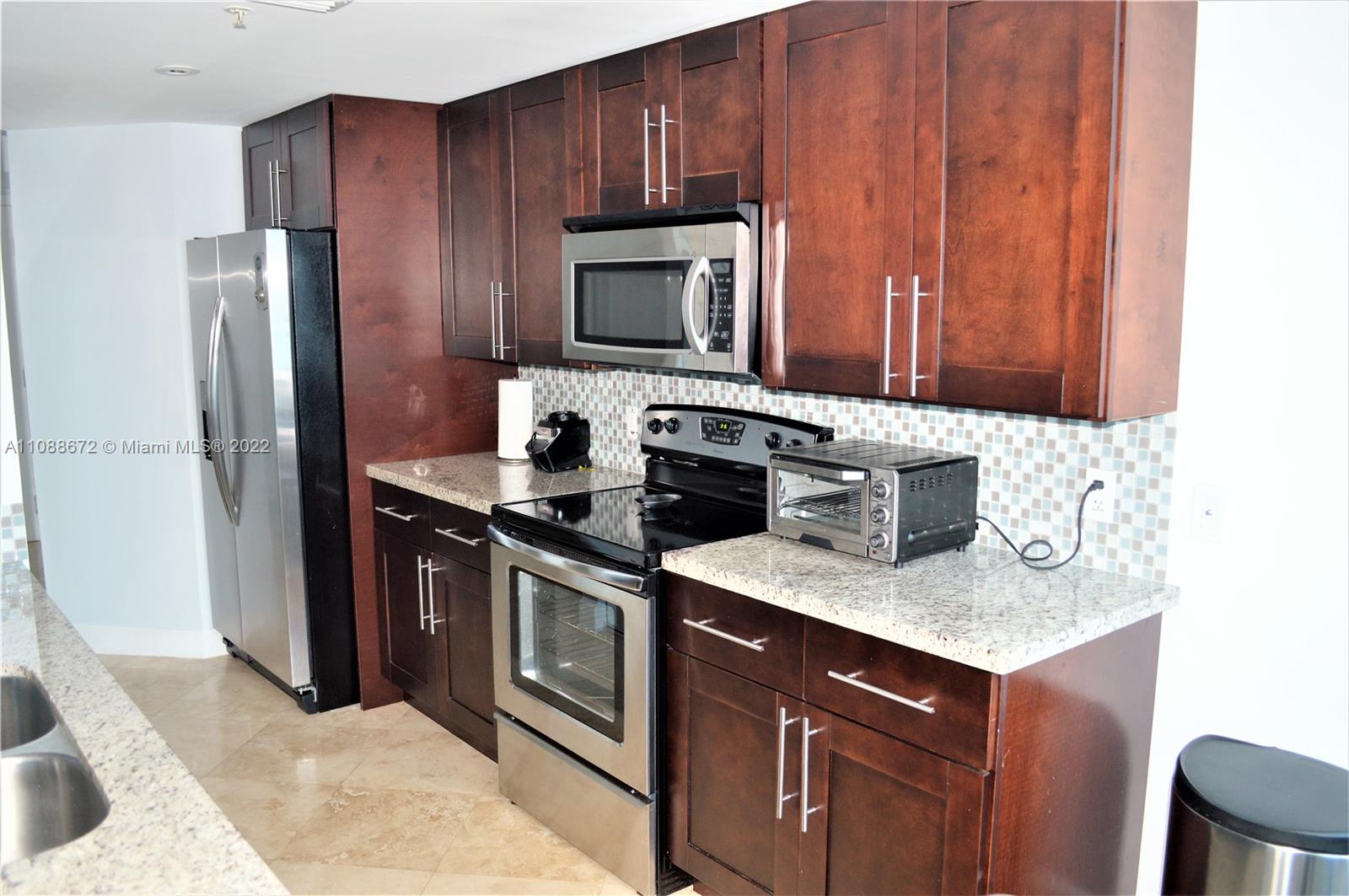 701 Brickell Key Boulevard, Unit 1203 Miami, FL 33131 - Photo 4 of 34 a kitchen with stainless steel appliances granite countertop a stove microwave refrigerator and sink