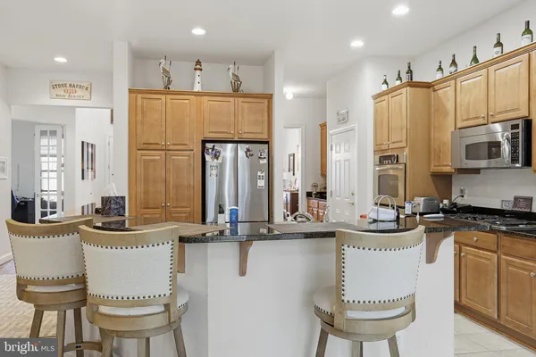 a kitchen with stainless steel appliances granite countertop a sink a stove and chairs