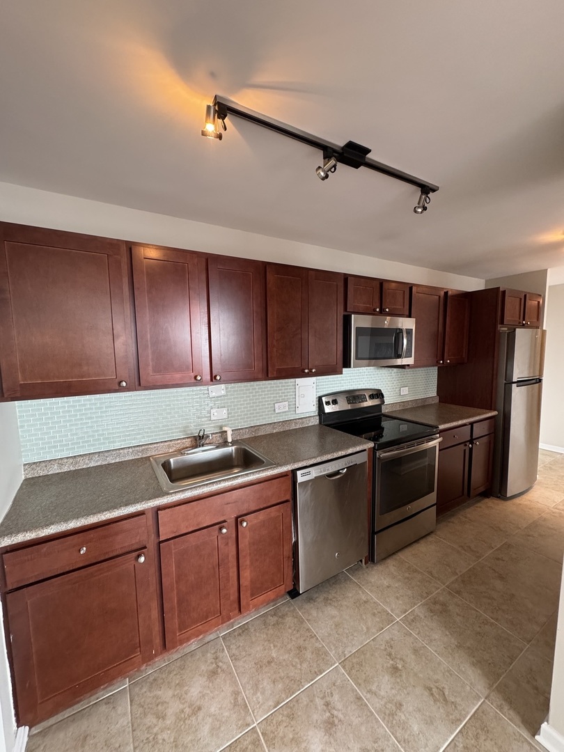 5701 North Sheridan Road, Unit 17S Chicago, IL 60660 - Photo 4 of 8 a kitchen with stainless steel appliances granite countertop a sink counter space cabinets and a stove
