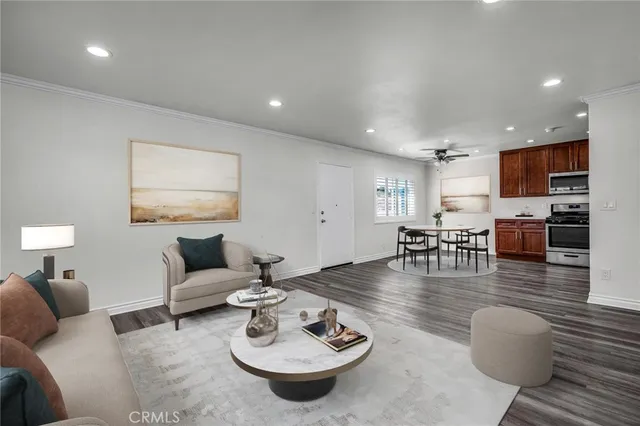 a living room with furniture kitchen view and a wooden floor