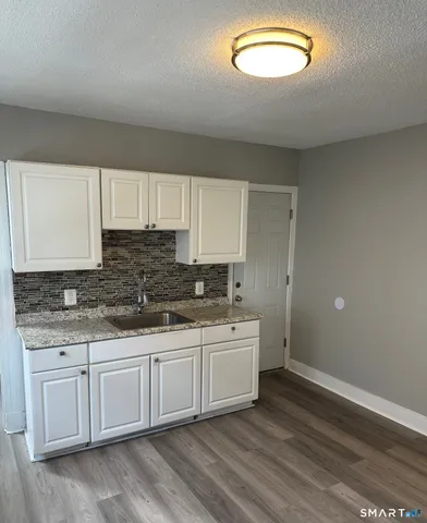 a kitchen with stainless steel appliances granite countertop a sink and cabinets with wooden floor