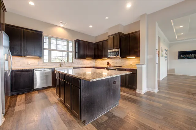 a kitchen with stainless steel appliances kitchen island granite countertop a stove a sink and a refrigerator