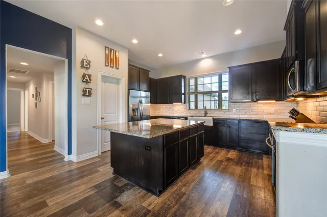 a kitchen with stainless steel appliances granite countertop a stove a sink and a refrigerator