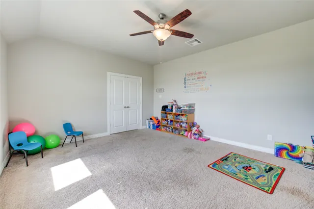 a view of play room with toys and ceiling fan