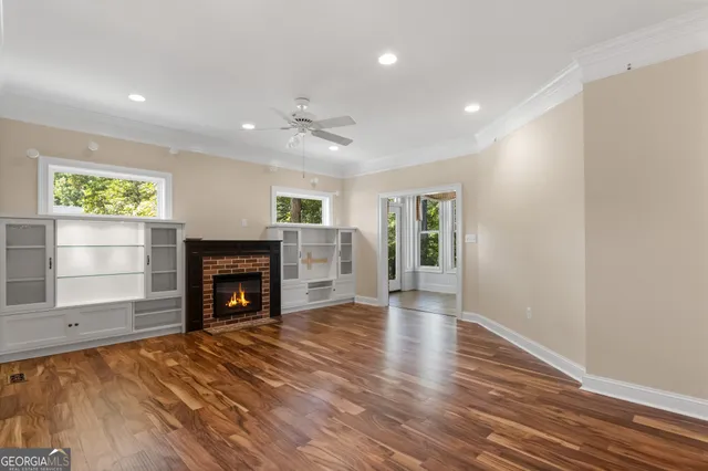 an empty room with windows a fireplace and wooden floor