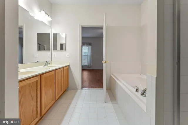 a bathroom with a double vanity sink mirror and bathtub