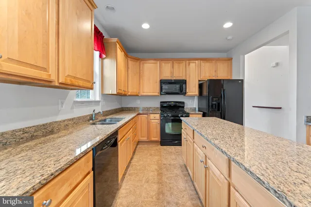 a kitchen with granite countertop a sink a counter space appliances and cabinets