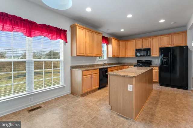 a kitchen with stainless steel appliances granite countertop a stove top oven a refrigerator a sink and dishwasher with wooden floor