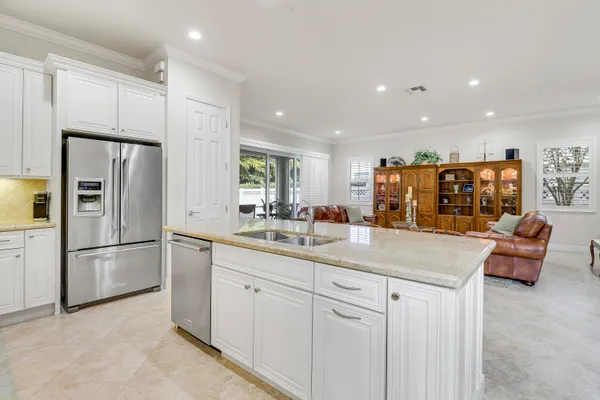 a kitchen with stainless steel appliances granite countertop a refrigerator a sink and white cabinets