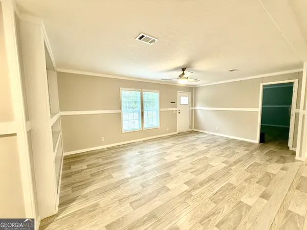 an empty room with wooden floor and windows