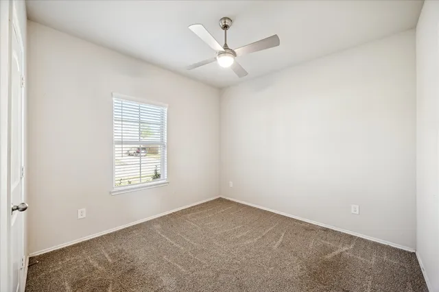 an empty room with windows and ceiling fan