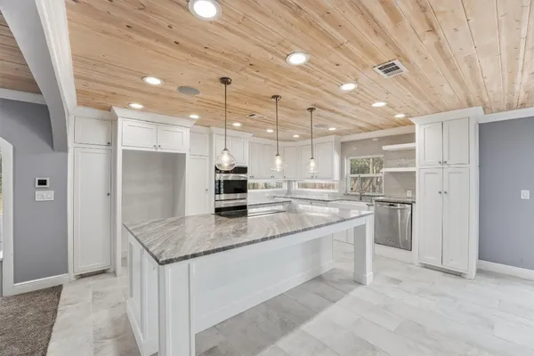 a large kitchen with kitchen island a sink stainless steel appliances and cabinets