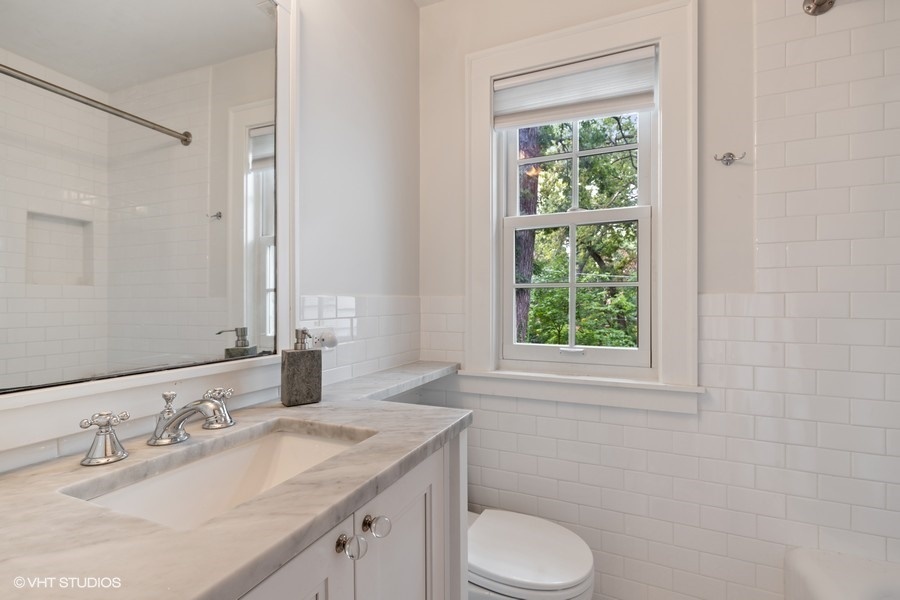 162 Maplewood Road Riverside, IL 60546 - Photo 35 of 44 a bathroom with a granite countertop toilet a sink a mirror and a window