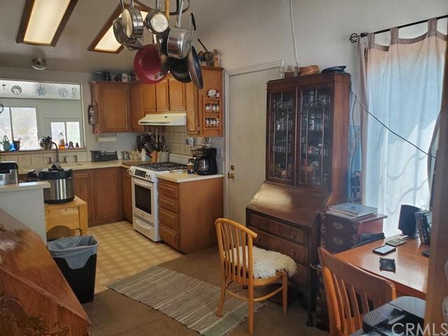12285 Golden View Road Pinon Hills, CA 92372 - Photo 17 of 33 a kitchen with stainless steel appliances granite countertop a sink dishwasher a stove a refrigerator a dining table and chairs with wooden floor
