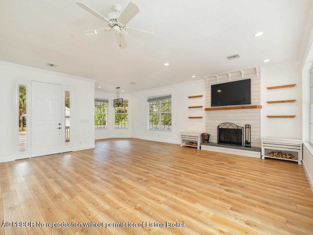 1001 Southeast Ranch Road Northeast Jupiter, FL 33478 - Photo 7 of 32 a view of a livingroom with a fireplace a chandelier and wooden floor