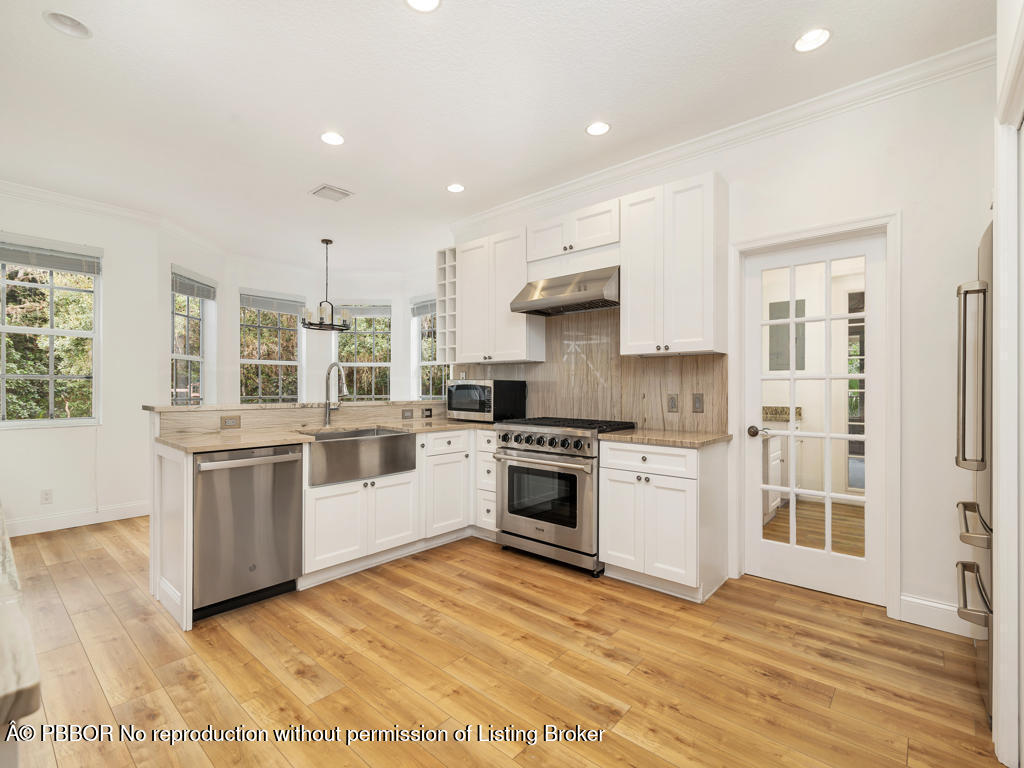 1001 Southeast Ranch Road Northeast Jupiter, FL 33478 - Photo 9 of 32 a kitchen with a white stove top oven and white cabinets