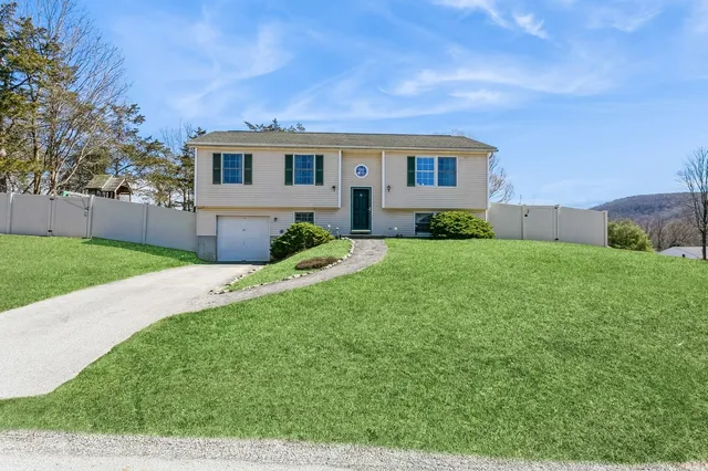 a backyard of a house with plants and large tree