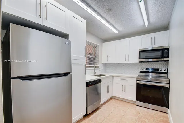 a kitchen with stainless steel appliances a refrigerator sink and white cabinets