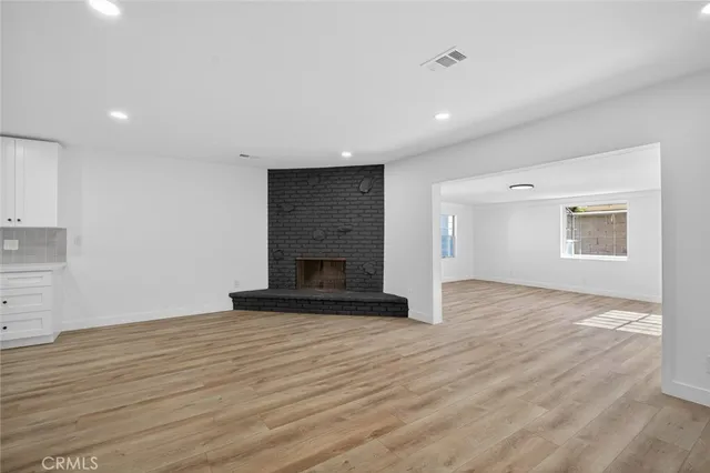a view of empty room with wooden floor and fireplace