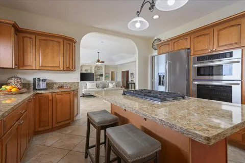 a kitchen with kitchen island granite countertop wooden cabinets and a refrigerator