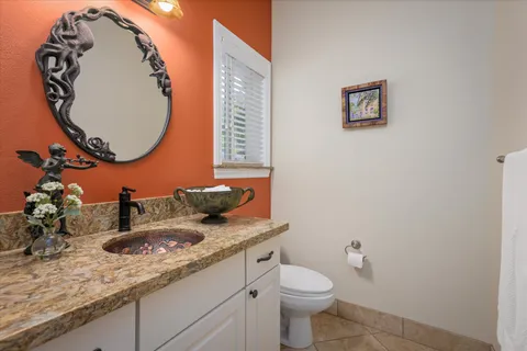 a bathroom with a granite countertop toilet sink mirror and vanity
