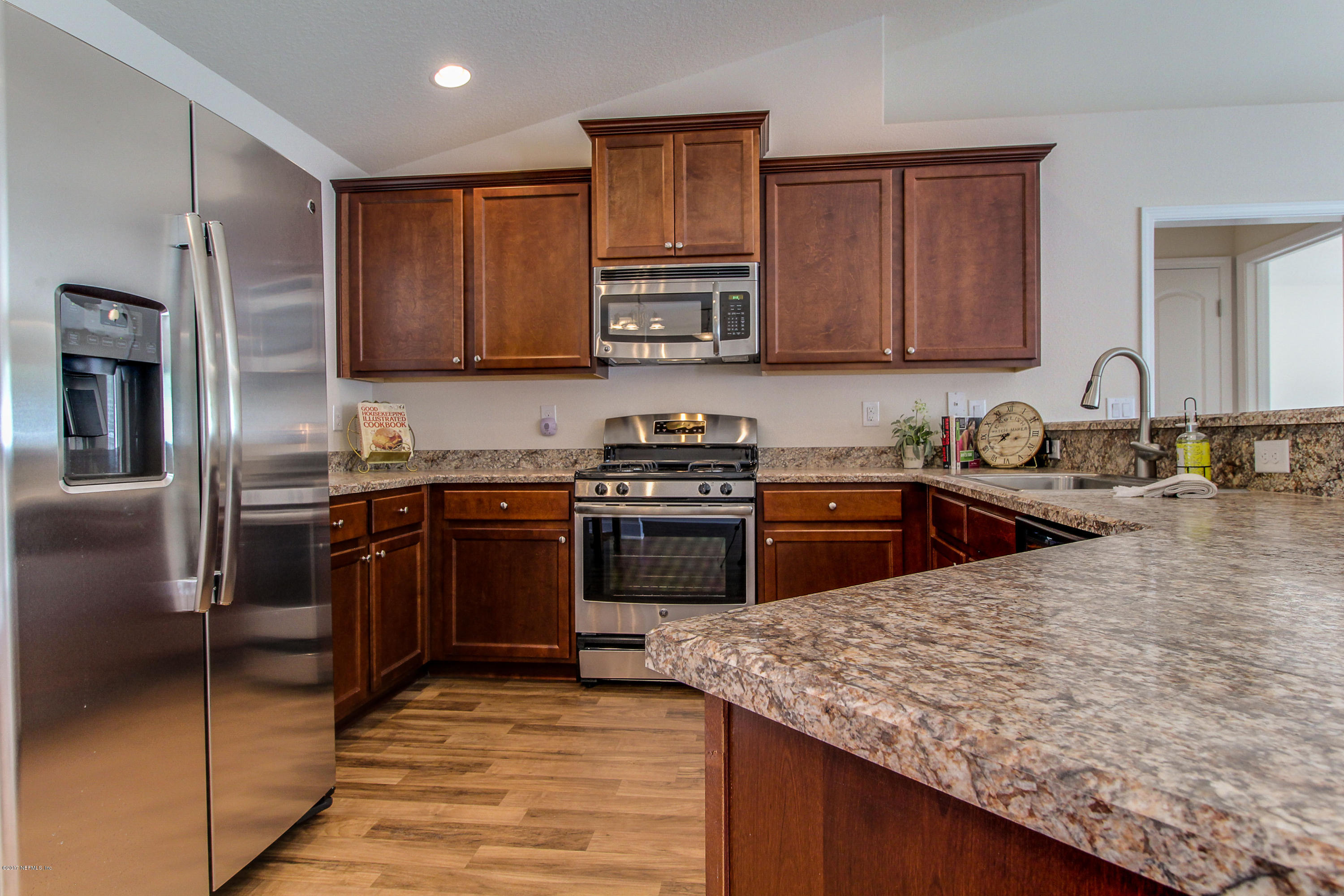 88442 Maybourne Road Yulee, FL 32097 - Photo 8 of 29 a kitchen with granite countertop stainless steel appliances and wooden cabinets