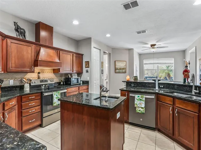 a kitchen with stainless steel appliances granite countertop wooden cabinets stove top oven and sink