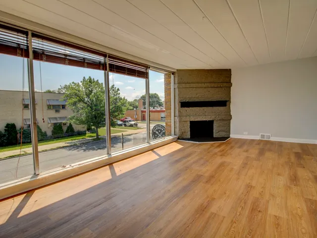 a view of empty room with wooden floor and fireplace