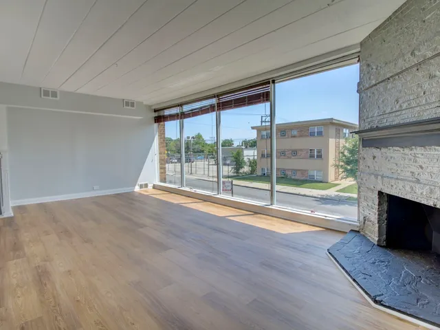 a view of empty room with wooden floor and fireplace