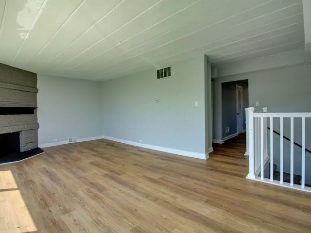 a view of empty room with wooden floor and fireplace