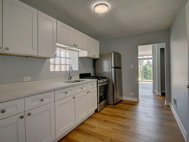 a kitchen with granite countertop white cabinets and refrigerator