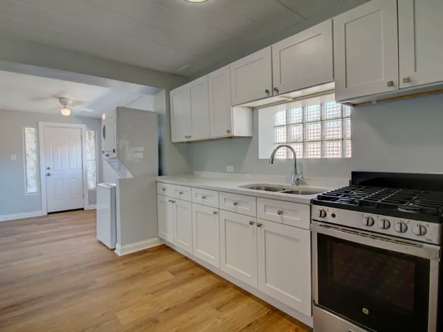 a kitchen with stainless steel appliances granite countertop a stove a sink and white cabinets