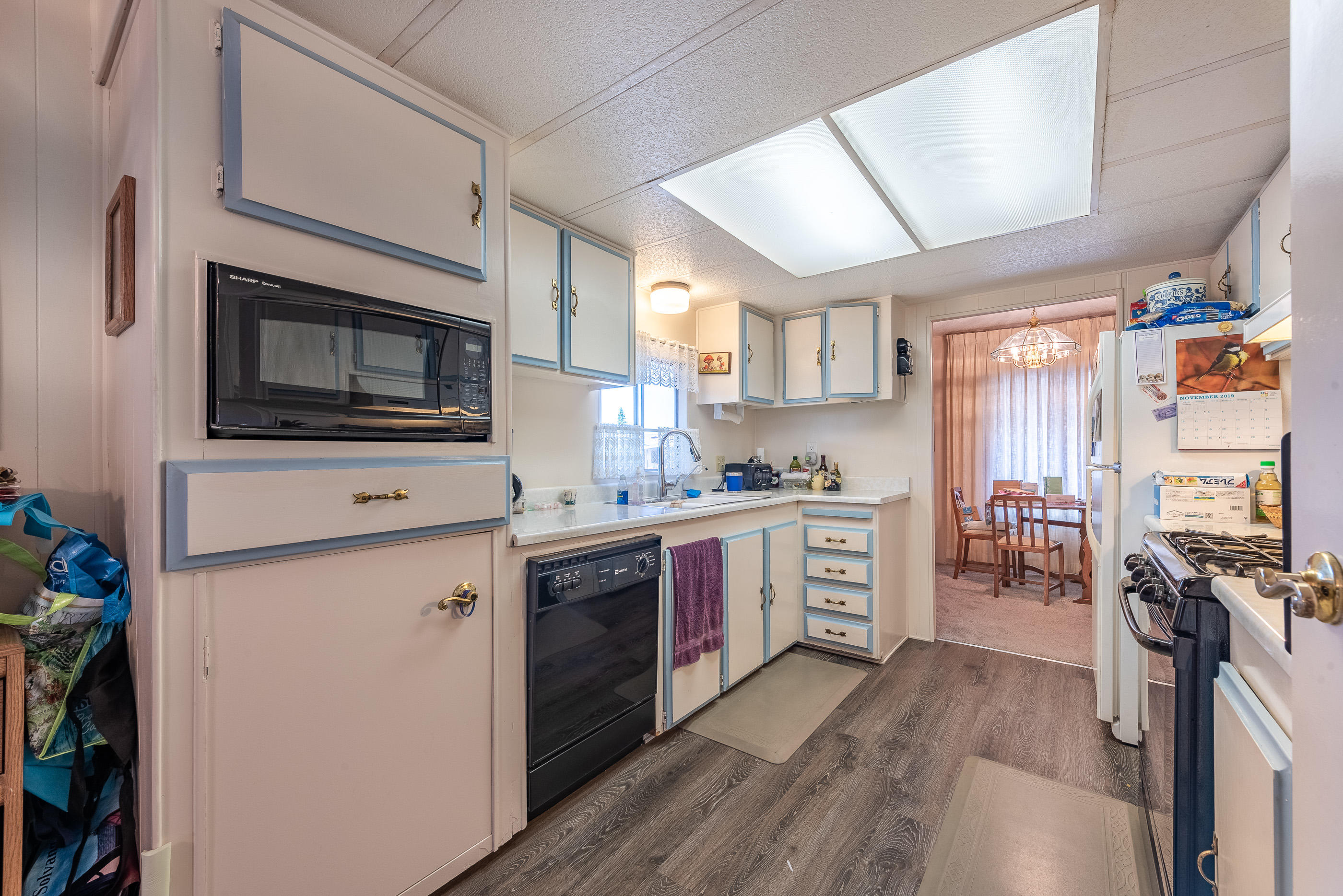 3950 Via Real, Unit 129 Carpinteria, CA 93013 - Photo 13 of 35 a kitchen with stainless steel appliances a stove top oven a sink dishwasher and a refrigerator with wooden floor