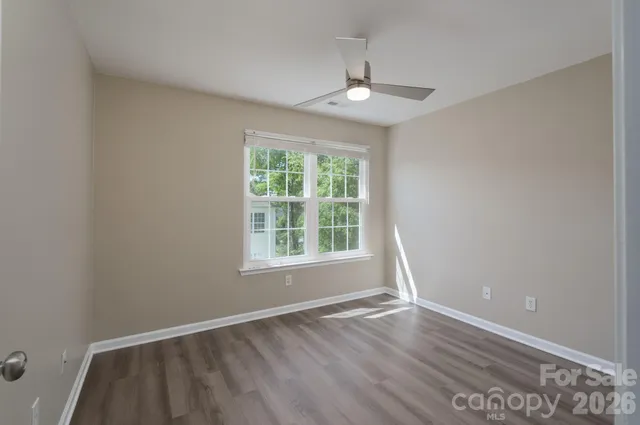 an empty room with wooden floor chandelier and window