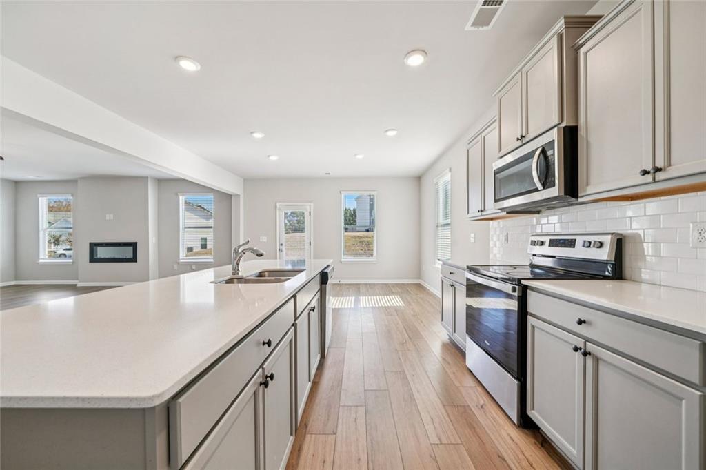 1547 Stinson Lane Locust Grove, GA 30248 - Photo 13 of 43 a large kitchen with stainless steel appliances granite countertop a lot of counter space and wooden floors