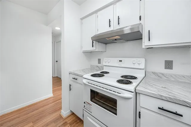 a kitchen with granite countertop a stove and a wooden floor