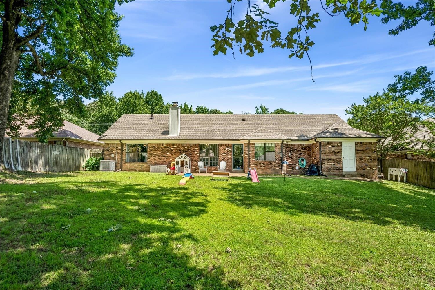 5711 Yale Road Bartlett, TN 38134 - Photo 27 of 29 Expansive backyard featuring a manicured lawn, mature trees, and a brick exterior with a pitched roof