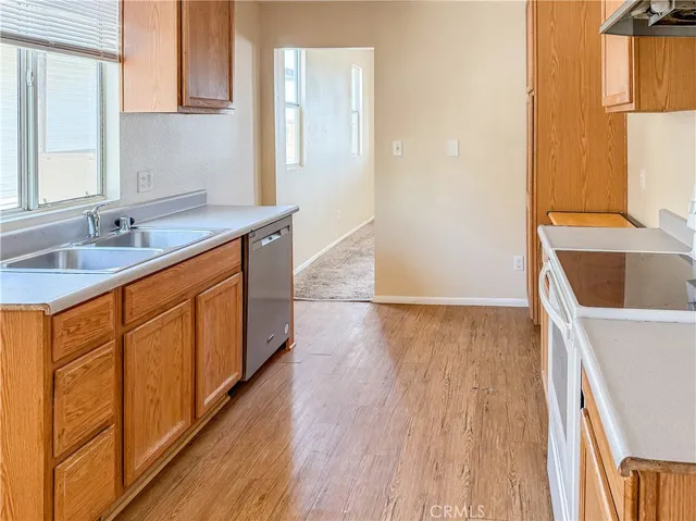a kitchen with stainless steel appliances granite countertop wooden cabinets a sink and dishwasher with wooden floor