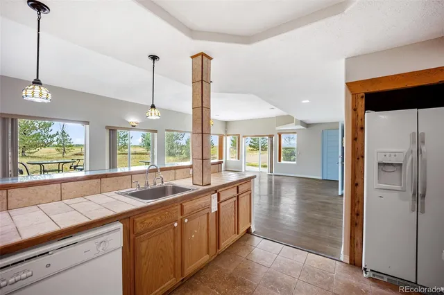 a large kitchen with kitchen island a large window a sink stainless steel appliances and cabinets