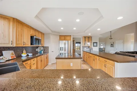 a large kitchen with stainless steel appliances granite countertop a large stove top oven a granite counter tops and a view of living room