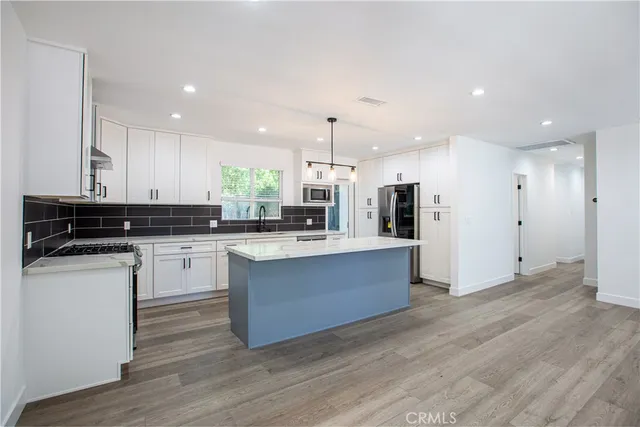 a kitchen with stainless steel appliances granite countertop a stove a sink and a refrigerator
