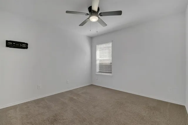 an empty room with a window and a fan
