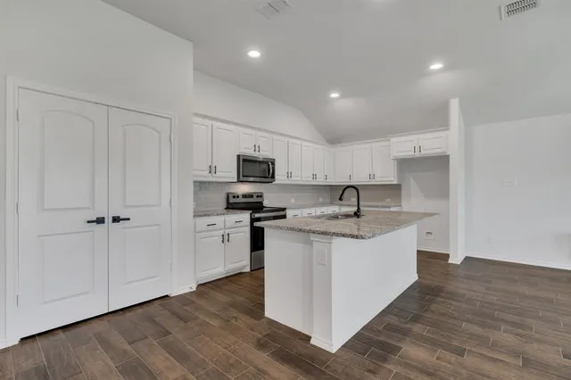 a large kitchen with stainless steel appliances granite countertop a sink and cabinets