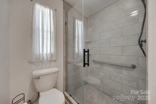 a white toilet sitting in a bathroom next to a window