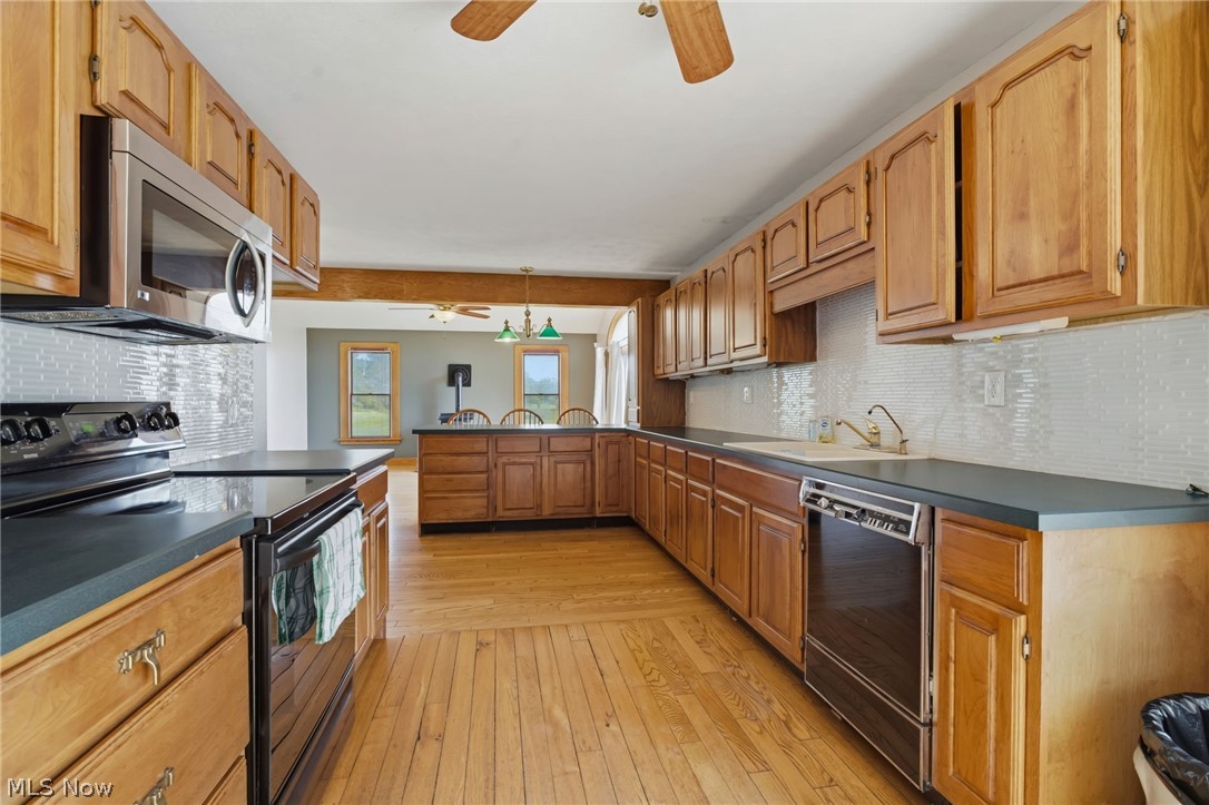11513 Kile Road Chardon, OH 44024 - Photo 12 of 48 Expansive kitchen featuring light wood cabinetry, dark green countertops, a tiled backsplash, wood flooring and appliances