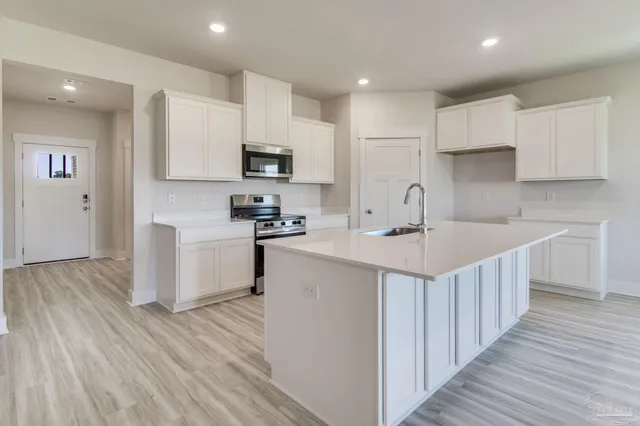 a kitchen with kitchen island white cabinets stainless steel appliances and sink