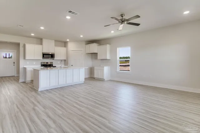 an open kitchen with wooden floor and stainless steel appliances